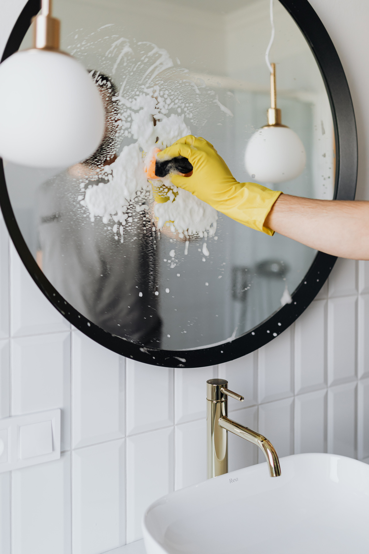 Faceless person cleaning mirror in bathroom